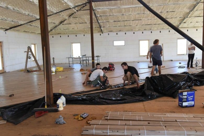 Horizontal image from the post "The Wood Floor Laying" showing family laying oak flooring.