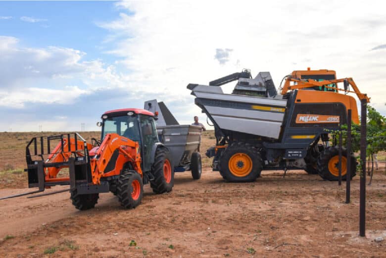 The tractor lining up behind the harvester; getting ready to dump.