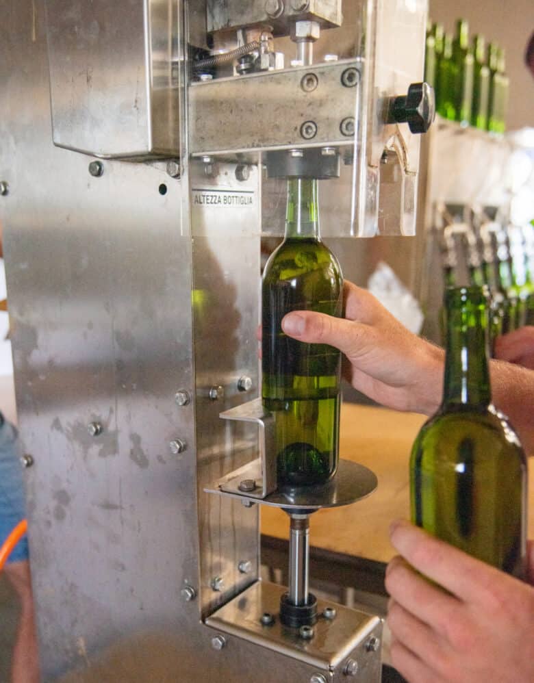 Bottling and Labeling Moscato 2019 - filled wine bottle getting corked.